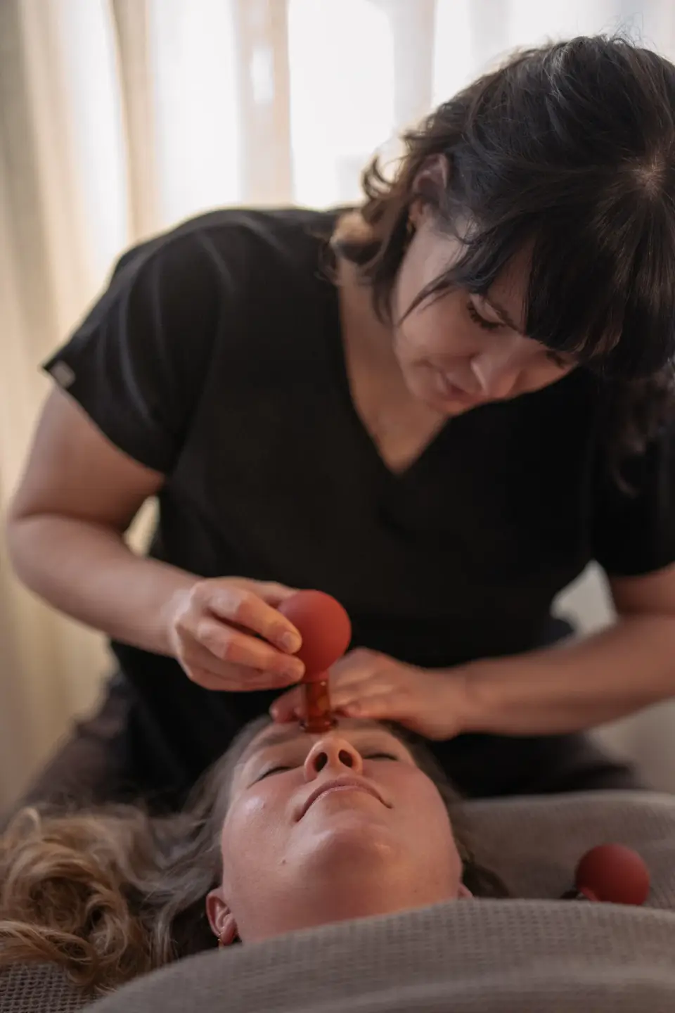 Kamila wykonująca zabieg na twarz z małą bańką — manualtherapies, Frederiksberg.